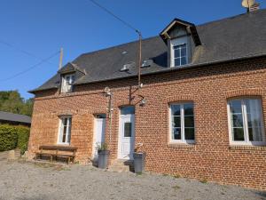 a red brick house with a white door at La Maison du temps retrouvé in Berville