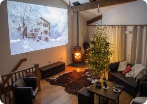 a living room with a christmas tree and a large screen at Chalet Broski - Spacious Chalet with Hot Tub, Sauna & BBQ in Planvillard