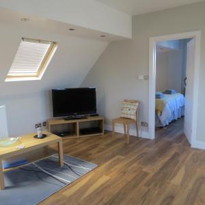 a living room with a television and a bed at Maltings Loft in Hepworth