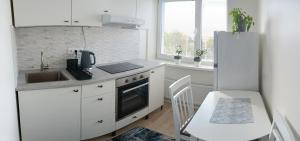 a white kitchen with a sink and a refrigerator at Uueka Külaliskorter in Kuressaare