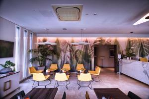 Eine Lobby mit gelben Stühlen, einem Tisch und einigen Pflanzen. in der Unterkunft Hotel Kuma in San Giuseppe