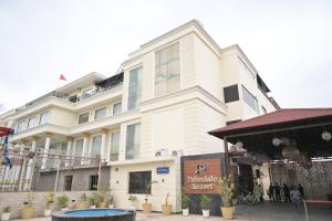 a large white building with people standing in front of it at Palmdale Hotel & Resort in Ambāla