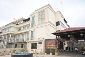 a large white building with a pool in front of it at Palmdale Hotel & Resort in Ambāla
