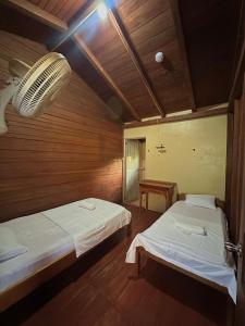 a room with two beds and a table in it at Hostal Yurag Wasi in Nuevo Rocafuerte