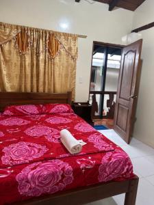 a bed with a red bedspread with a towel on it at Hostal Yurag Wasi in Nuevo Rocafuerte