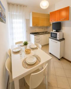 a kitchen with a white table with chairs and a kitchen with at Residence Caorle Apartments - Agenzia Cocal in Caorle +18 photos