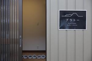 ein Schild an der Wand eines Zimmers mit einer Tür in der Unterkunft 民宿プラトーハウス in Namerikawa