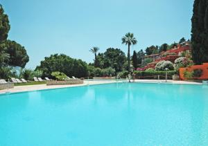 a large blue swimming pool with palm trees in the background at Appartamenti Capo d'Arco in Capo D'Arco