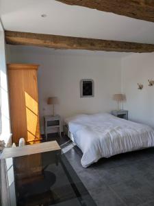 a bedroom with a white bed and a table at La Maison du temps retrouvé in Berville