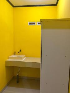 a bathroom with a sink and a yellow wall at Kurniawan Homestay in Pulau Sarang