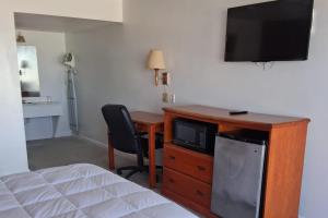 a room with a bed and a desk with a television at Coratel Inn and Suites By Jasper Anthony in Anthony