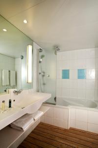 biała łazienka z wanną i umywalką w obiekcie Novotel Lisboa w Lizbonie