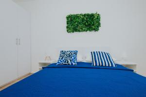 a bedroom with a blue bed with a plant on the wall at Villa Iva-Dom in Kaštela