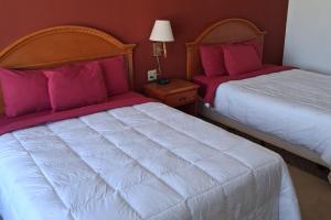 two beds in a hotel room with pink pillows at Coratel Inn and Suites By Jasper Anthony in Anthony