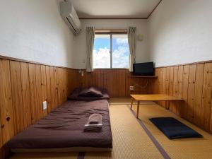 a room with two beds and a table and a window at Hostel Mosura no Tamago in Motobu +55 photos