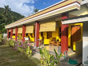 a yellow and red building with tables and chairs at Kurniawan Homestay in Pulau Sarang