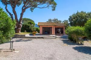 a small house with a tree and a gravel driveway at Villino Francesca in Portoferraio