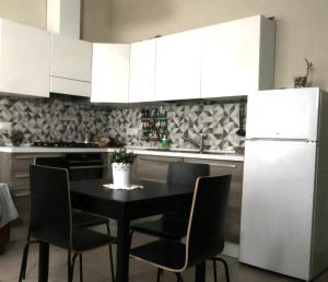 a kitchen with a black table and chairs and a white refrigerator at TOSCANA HOME in Ravenna