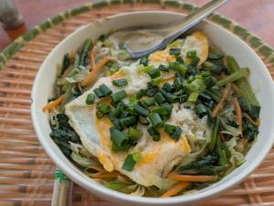 a bowl of food with chicken and vegetables with a spoon at Mắn Mẩy homestay in Tả Van