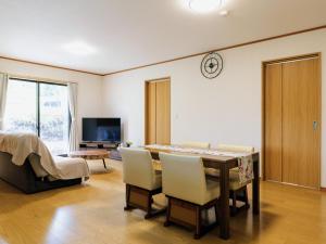 a living room with a table and chairs and a tv at Holiday Home 郷 in Minami Aso