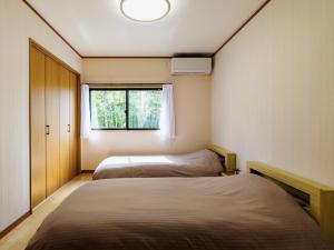 two beds in a small room with a window at Holiday Home 郷 in Minami Aso