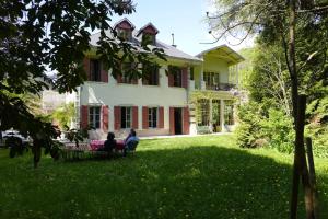 two people sitting on a lawn in front of a house at La maison des jours heureux in Leysse