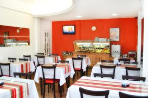 Arpini Hotel في ريو غراندي: مطعم بطاولات بيضاء وكراسي وجدران حمراء