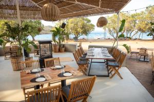 a restaurant with wooden tables and chairs and the beach at The Beach House at Oz Bay in Pantoukiós