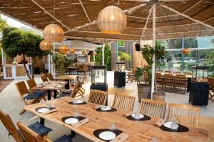 a restaurant with wooden tables and chairs and large windows at The Beach House at Oz Bay in Pantoukiós