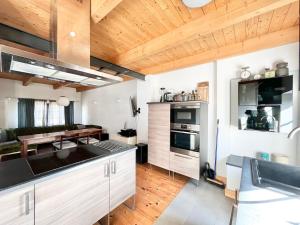 a kitchen with white cabinets and a wooden ceiling at Kachelofenhaus in Fehmarn +17 photos