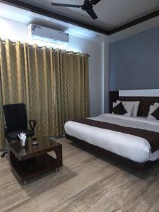 a bedroom with a bed and a chair and a table at Hotel Welcome inn in Patna
