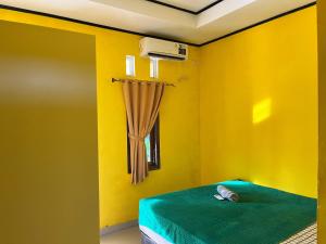 a yellow room with a bed and a window at Kurniawan Homestay in Pulau Sarang