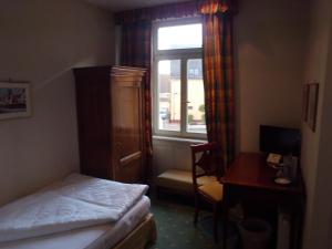 Schlafzimmer mit einem Bett, einem Schreibtisch und einem Fenster in der Unterkunft Hotel Freihof in Wiesloch