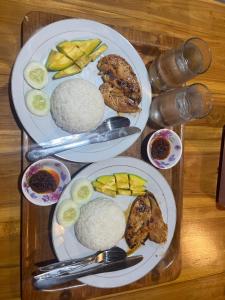 two plates of food with rice and fruit on a table at Kurniawan Homestay in Pulau Sarang