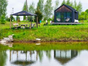 a gazebo and a picnic table next to a lake at Forest edge in Saugos