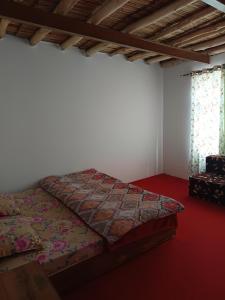 a bed in a room with a red floor at White rose homestay in Kaza