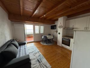 a living room with a couch and a kitchen with a table at Studio apartman i sobe SIDRO in Karlobag