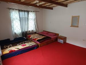 two beds in a room with a red carpet at White rose homestay in Kaza