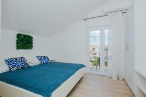 a white bedroom with a bed and a balcony at Villa Iva-Dom in Kaštela