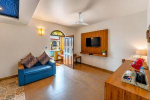 a living room with a blue couch and a tv at Resort Terra Paraiso Goa - A Beach Property in Calangute