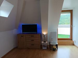 a room with a tv on a dresser with a window at Lou Castelou Pont d'Estaing in Sébrazac
