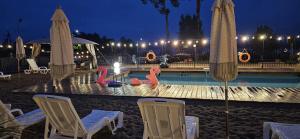 a swimming pool with chairs and umbrellas at night at SELMENT RESORT & SPA - Mazury in Ełk