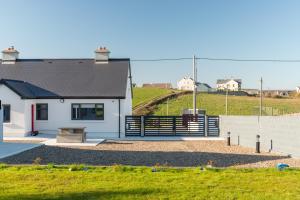 a white house with a bench in a yard at Gorgeous Luxury in Lahinch