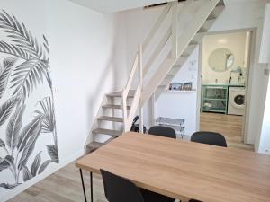 a dining room with a table and a staircase at L'ESPOIRENTHESE T2 35m2 in Nieuil-lʼEspoir +7 photos