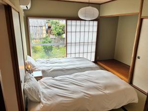 two beds in a room with a window at Recasa in Imabari