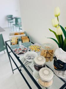 a glass table topped with food and a vase with flowers at Xenia Room in Gela