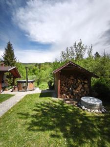 a building with a pile of logs in the grass at Chata U Jozefa in Malý Lipník