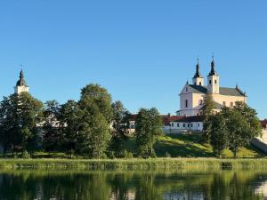 a castle on a hill next to a body of water at Pokamedulski Klasztor w Wigrach in Wigry