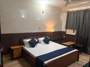 a bedroom with a bed with blue and white pillows at Hotel Gangotri in Bahāsi