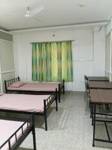 a room with three beds and tables and a window at Nasa Hostel in Panchanai +3 photos
